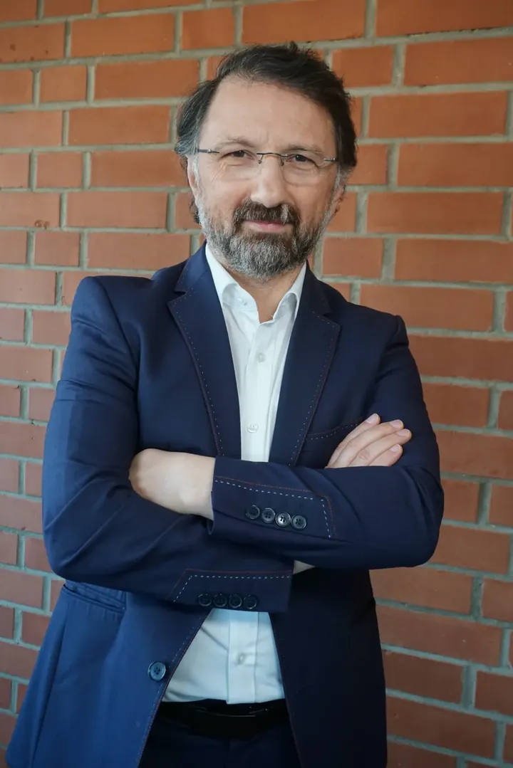Mustafa Cimşit vor einer Backsteinmauer